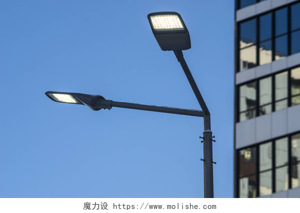 蓝天下的高楼和路边的路灯一根现代化的街道 led 照明杆。城市电力能源技术。街道城市道路照明的节省.